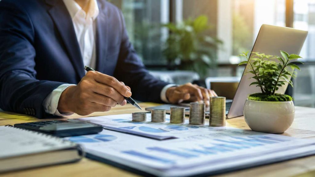 Business professional analyzing financial growth and business strategy with charts and increasing coin stacks.